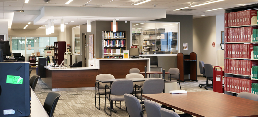 Inside of the FIMS Grad Library, with chairs, tables and a circulation desk.